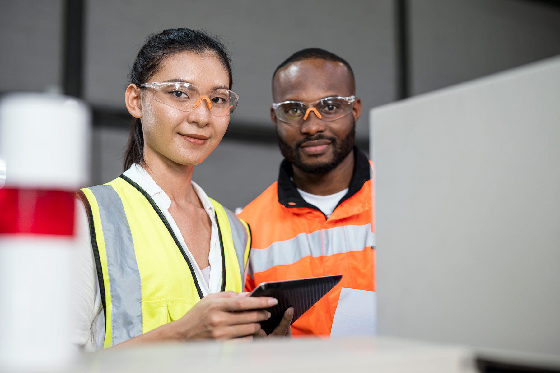 2 diverse workers wearing protective uniforms and smiling