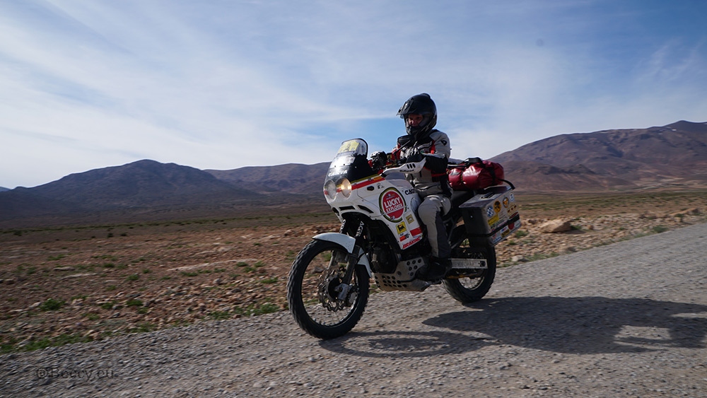 Rebecca Kleis riding motorcycle along mountain lined road