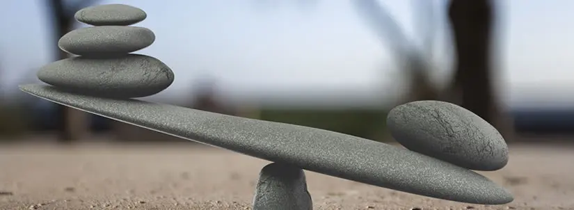 Three stones on one end and one stone on another depicting weight balance