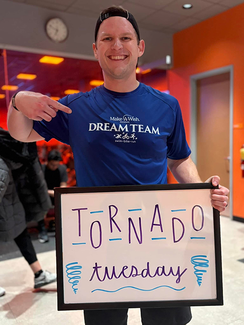 Mann zeigt auf ein Schild mit der Aufschrift „Tornado Tuesday“ in einem Fitnessstudio
